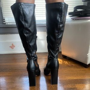 Black high heel boots with a gold lie around them.